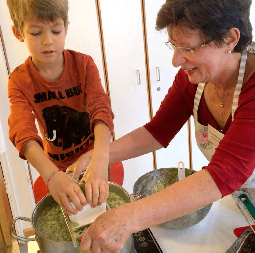 Kind und Frau mit Schürze am Kochtopf