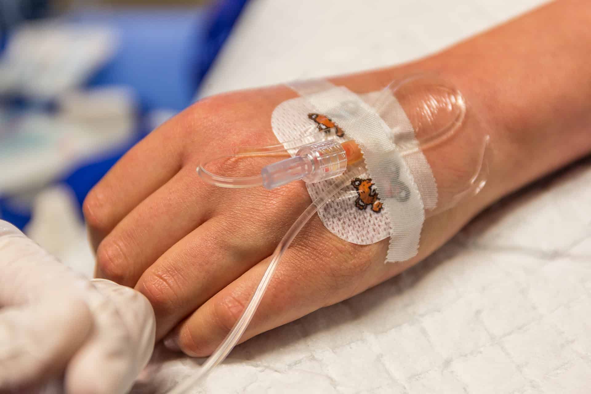 Hand mit Infusionsnadel und -Schlauch