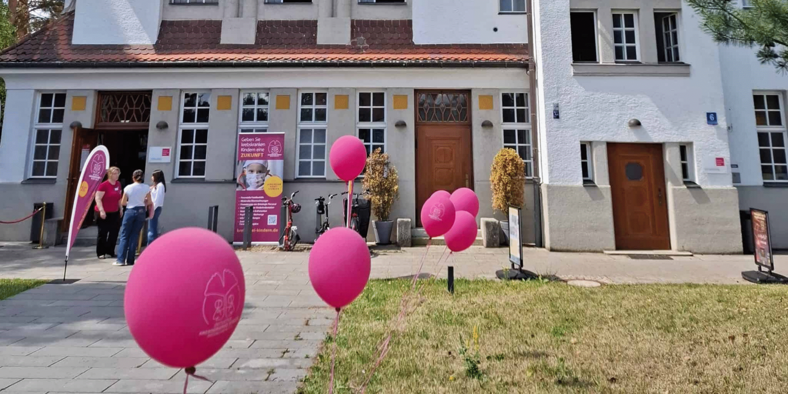 Pinke Ballons vor einem Gebäude bei einer Veranstaltung – Jobs und Engagement für krebskranke Kinder