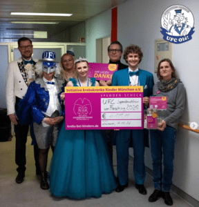 7 Personen auf dem Klinikgang mit Spendenscheck