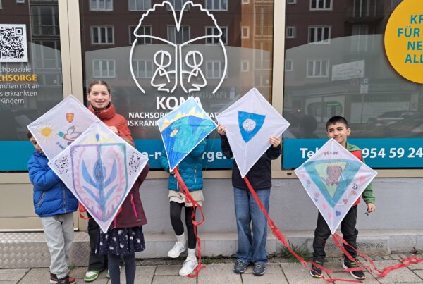 6 Kinder stehen vor dem Büro und halten selbstgebastelte Flugdrachen