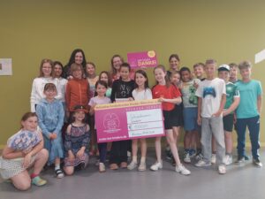 Viele Kinder und Lehrerinnen mit Spendenscheck