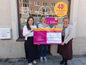 3 Frauen mit Spendenscheck vor dem Bürofenster