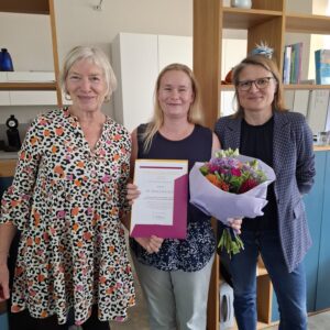 3 Frauen, die mittlere mit Urkunde und Blumenstrauss