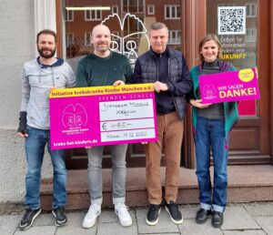 4 Personen mit Spendenscheck vor dem Büro
