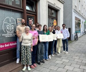 12 Personen mit Urkunden vor dem Ladenbüro