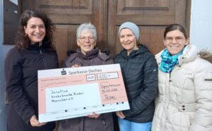 4 Frauen mit Spendenscheck vor einer Tür