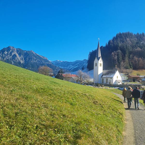 Wanderer im Gebirge mit Kirche und Häusern