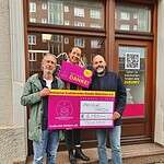 Zwei Männer halten einen Spendenscheck. Eine Frau dazwischen eine "Danke"-Karte