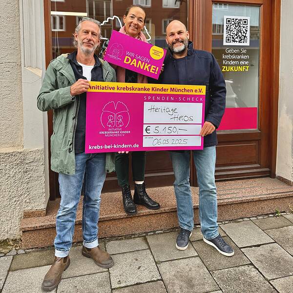 Zwei Männer halten einen Spendenscheck. Eine Frau dazwischen eine "Danke"-Karte