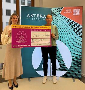 2 Frauen vor Werbewand halten Spendenscheck