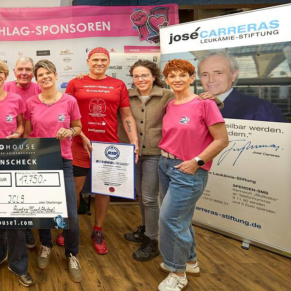 10 Personen präsentieren auf der Bühne einen Spendenscheck