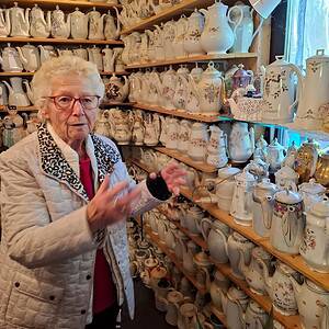 Frau vor Regalen mit Kaffeekannen