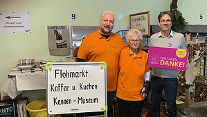 2Männer und eine Frau hinter Flohmarktschild